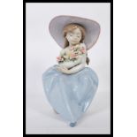 A Lladro porcelain figure entitled ' Fragrant Bouquet ' depicting a girl seated on a rock,