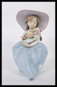 A Lladro porcelain figure entitled ' Fragrant Bouquet ' depicting a girl seated on a rock,