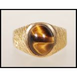 A stamped 9ct gold vintage 1970's ring set with an oval tigers eye cabochon to the head having