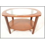 A 20th Century retro teak wood circular coffee table with drop in glass centre raised on shaped