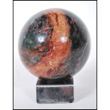 A precious stone rhodonite specimen sphere having red and green mottled colouration, on a chromed