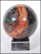 A precious stone rhodonite specimen sphere having red and green mottled colouration, on a chromed