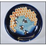 A Moorcroft Honeycomb pattern plate having blue ground with tubelined honeycomb and bee