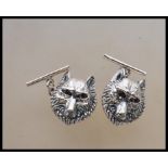 A pair of silver wolf mask gents cufflinks. Each with wolf head design having chain backs. Verso