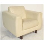 A retro cream leather armchair by Habitat raised on saquer wooden supports. Measures 82cms x 94cms x