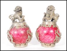 A pair of Chinese red marble desktop ornaments constructed from marble globes with applied silver