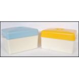 A pair of mid 20th Century retro bread bins, one having a yellow top and the other a blue top with