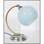 A Art Deco desk / table lamp, having a chrome circular base, brass bend support and a baby blue