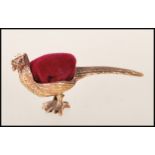 An unusual pin cushion in the form of a pheasant. The brass body with a red baize cushion top.