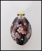 A 20th Century Chinese carved purple stone snuff bottle having faceted edges and enamelled blossom