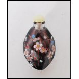A 20th Century Chinese carved purple stone snuff bottle having faceted edges and enamelled blossom