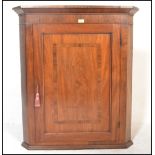 An 18th / 19th Century Georgian oak and mahogany crossbanded hanging corner cupboard enclosed by a