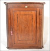 An 18th / 19th Century Georgian oak and mahogany crossbanded hanging corner cupboard enclosed by a