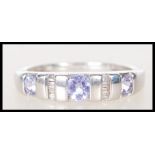 A stamped 375 9ct white gold ring channel set with three purple stones having baguette diamond