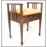 An early 20th Century Edwardian mahogany piano stool with upholstered lifting top, scroll arms and