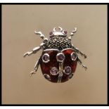 A silver and enamel bug brooch. The brooch in the form of a ladybird with red body and inset
