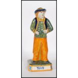 A 19th Century French Victorian ceramic faience figurine of a brightly glazed gentleman in had