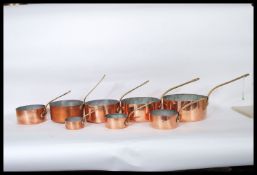 A set of eight 20th Century graduating copper saucepans, each fitted with brass riveted handles.