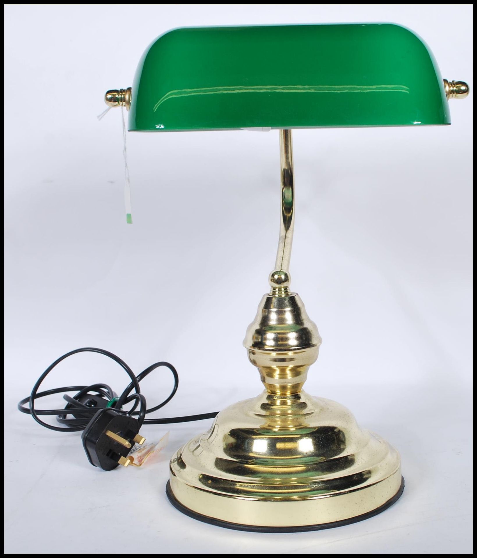 A vintage style bankers desk lamp having an adjustable green glass shade raised on a brass support