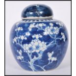 A Chinese ginger jar being hand painted in blue and white in the prunus pattern with lid to the top.