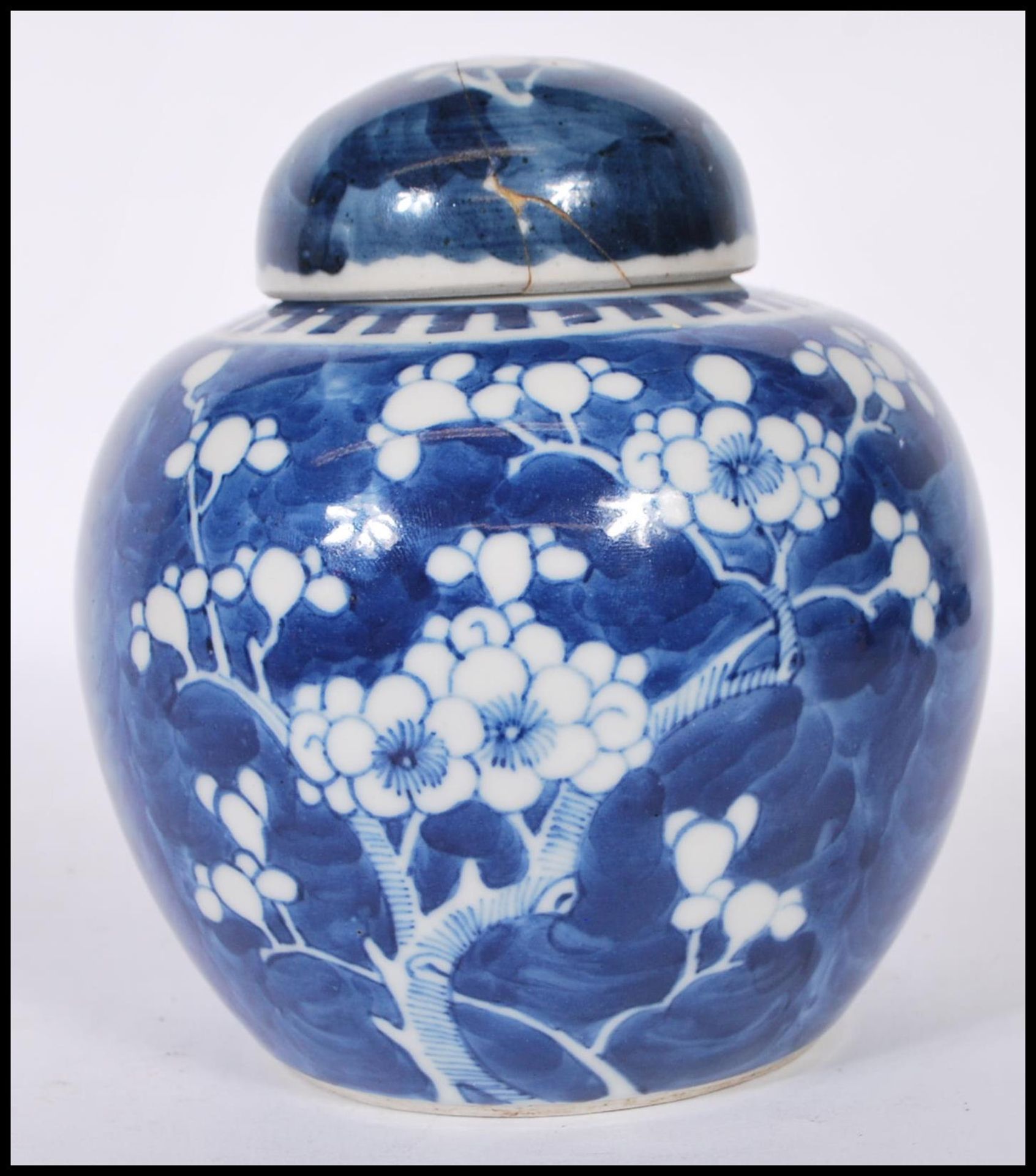 A Chinese ginger jar being hand painted in blue and white in the prunus pattern with lid to the top.