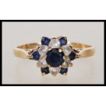 A hallmarked 9ct gold ring having a flower head set with blue and white stones. Hallmarked