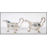 A pair of large late Victorian silver hallmarked gravy boats being raised on pad hairy paw feet.