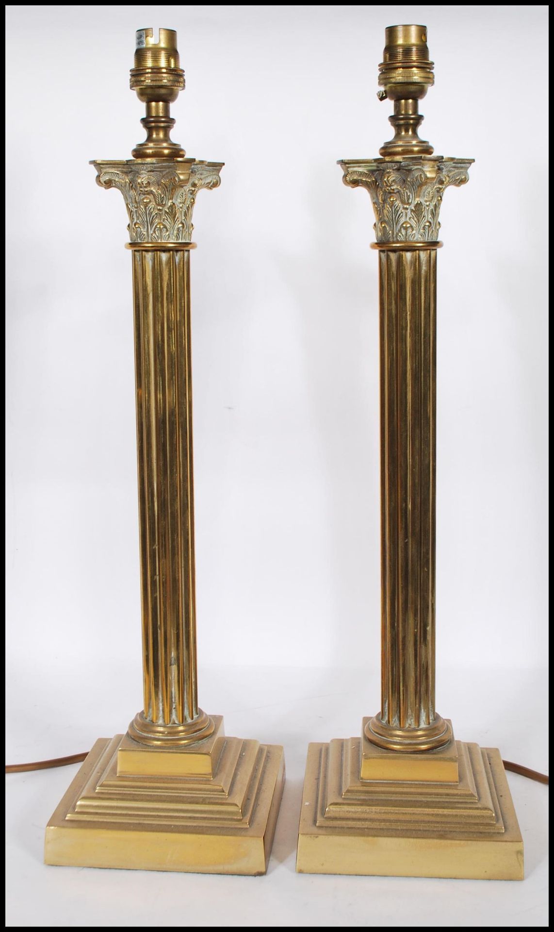 A matching pair of 20th Century brass corinthian column lamps of typical form raised on stepped