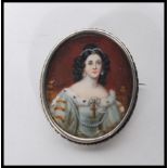 A 19th Century portrait miniature depicting a lady in a fur lined dress set into a silver brooch
