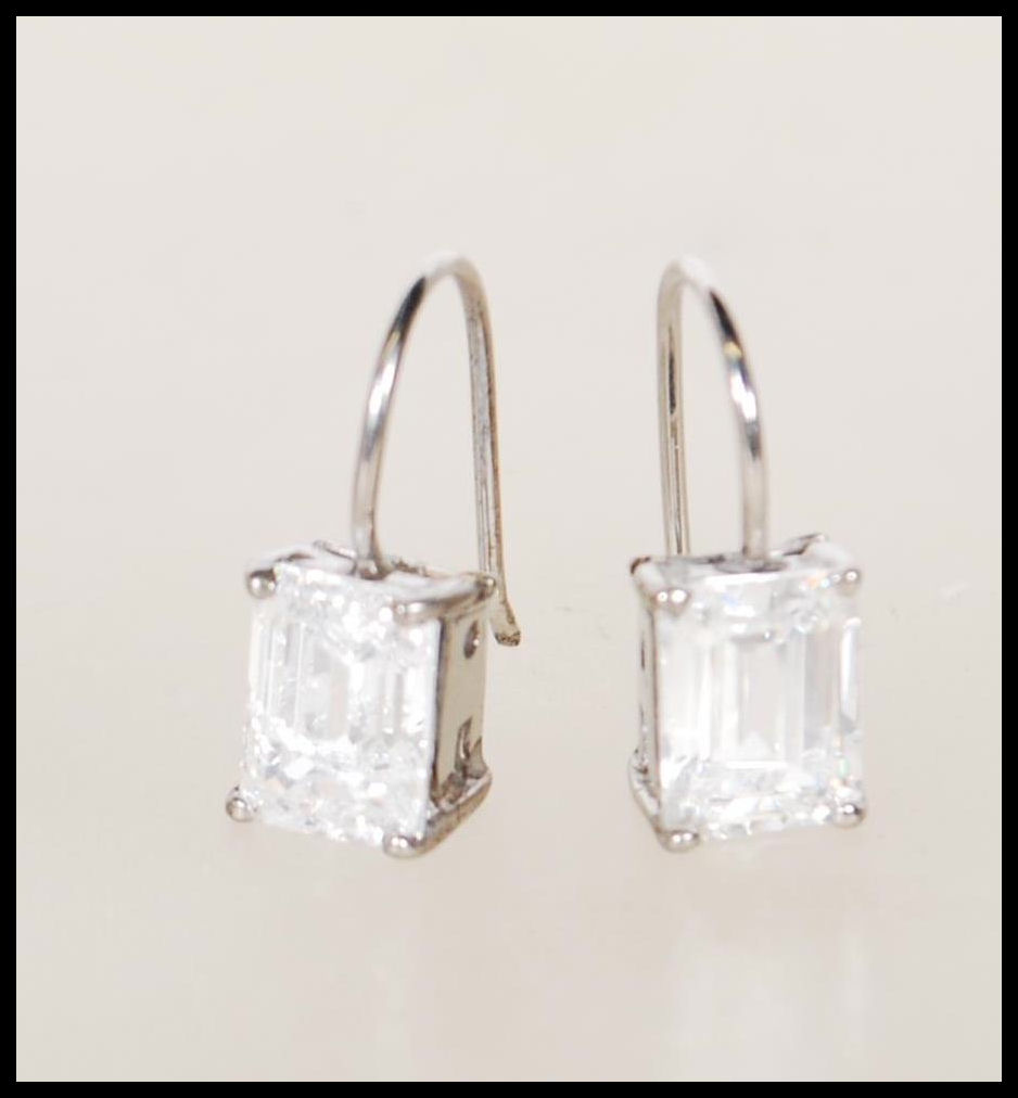 A pair of silver and emerald cut cz stone ladies earrings in claw mounts with hoop backs. Total