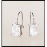 A pair of silver and emerald cut cz stone ladies earrings in claw mounts with hoop backs. Total