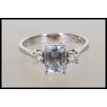 An 18ct white gold aquamarine and diamond ring, The cushion cut aquamarine with two round