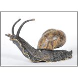 A cast bronze sculpture ornament in the form of a snail having a cold painted shell, signed to the