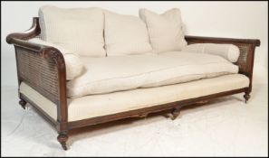 A good early 20th century large Edwardian mahogany bergere twin caned sofa. Raised on bun feet