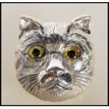 An unusual ladies silver brooch in the form of a cats head with glass eyes. Pin verso. Measures 3cms