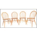 A set of four mid 20th century Ercol Windsor Quaker style hoop-back dining chairs in light elm and