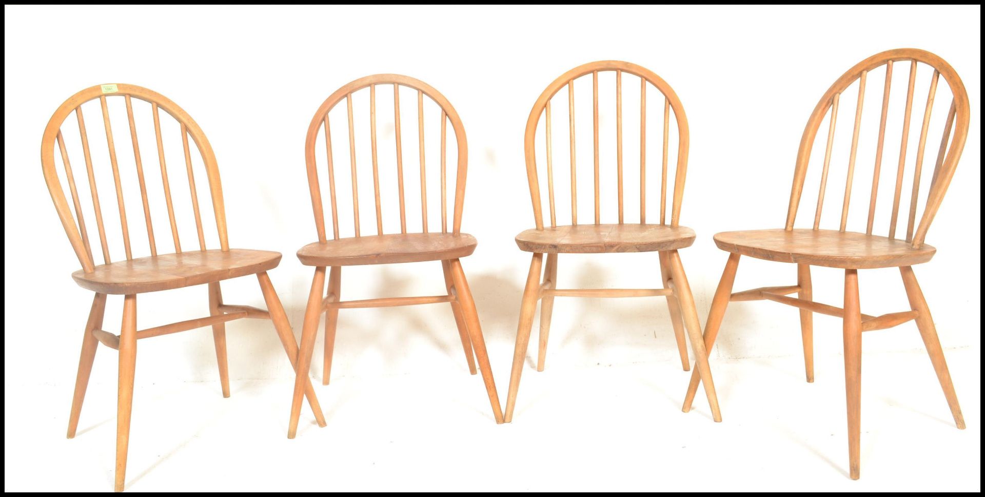 A set of four mid 20th century Ercol Windsor Quaker style hoop-back dining chairs in light elm and