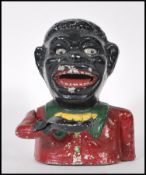 A vintage 20th Century cast iron money bank, being cold painted in black and red with a mechanical