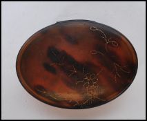 A 19th Century Georgian tortoise shell patch box of oval form having gilt floral inlay to the lid.