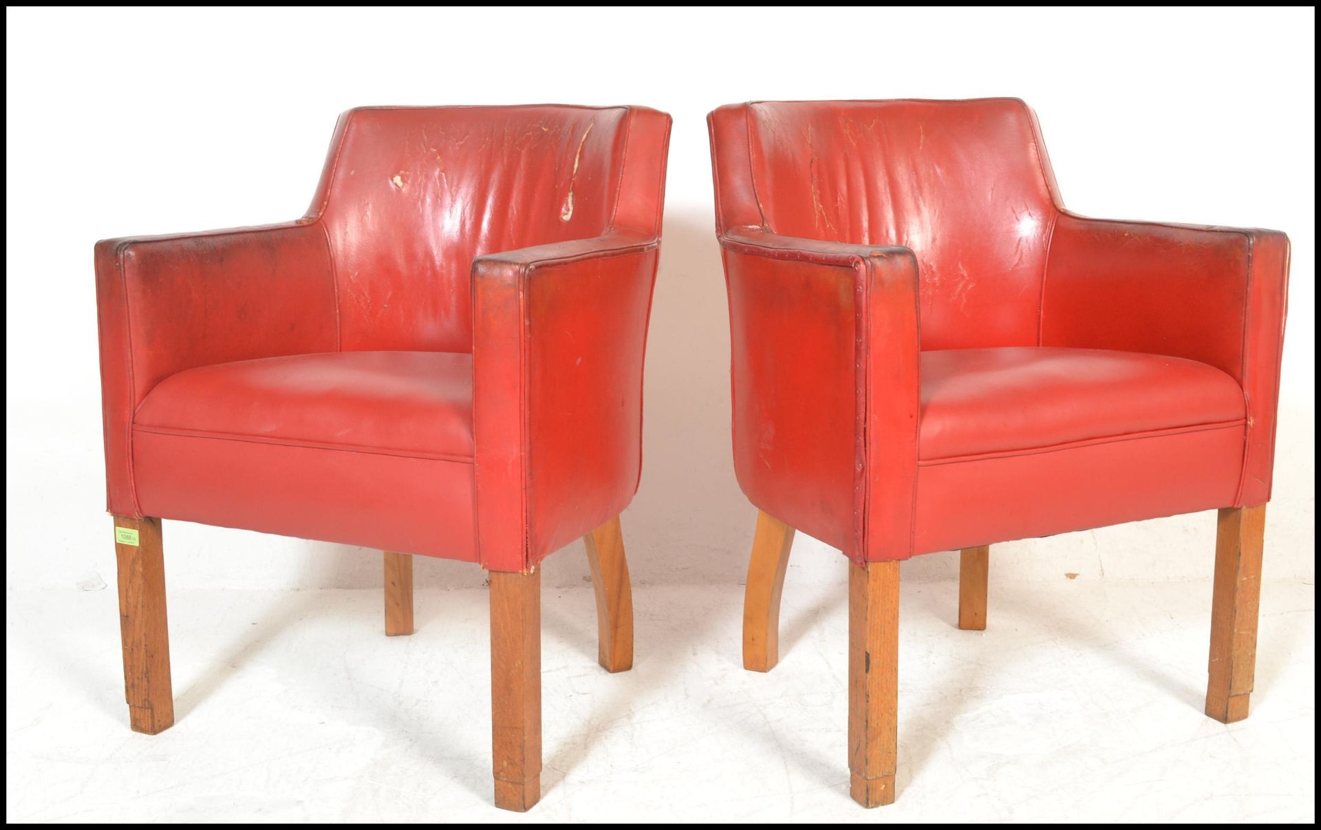 A pair of mid 20th Century tub / club / armchairs, raised on beech square supports, upholstered in