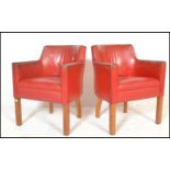 A pair of mid 20th Century tub / club / armchairs, raised on beech square supports, upholstered in