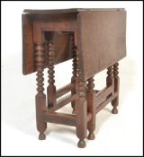 A 17th century country oak drop leaf table. Raised on bobbin turned supports with peg jointed
