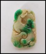 A carved Chinese green stone / jadite amulet pendant having carved animal detailing including a