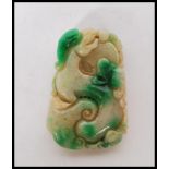 A carved Chinese green stone / jadite amulet pendant having carved animal detailing including a