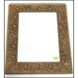An early 20th Century wall mirror of rectangular form having an embossed brass frame with scallop