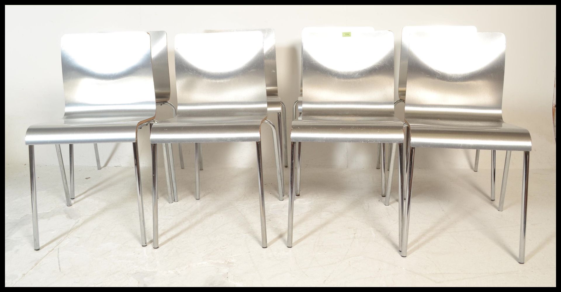 A set of eight panel stacking dining  chairs, the chairs panels having a silvered finish raised on