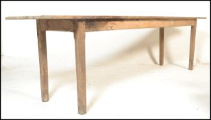 A large 19th century rustic French country pine refectory dining table being raised on squared