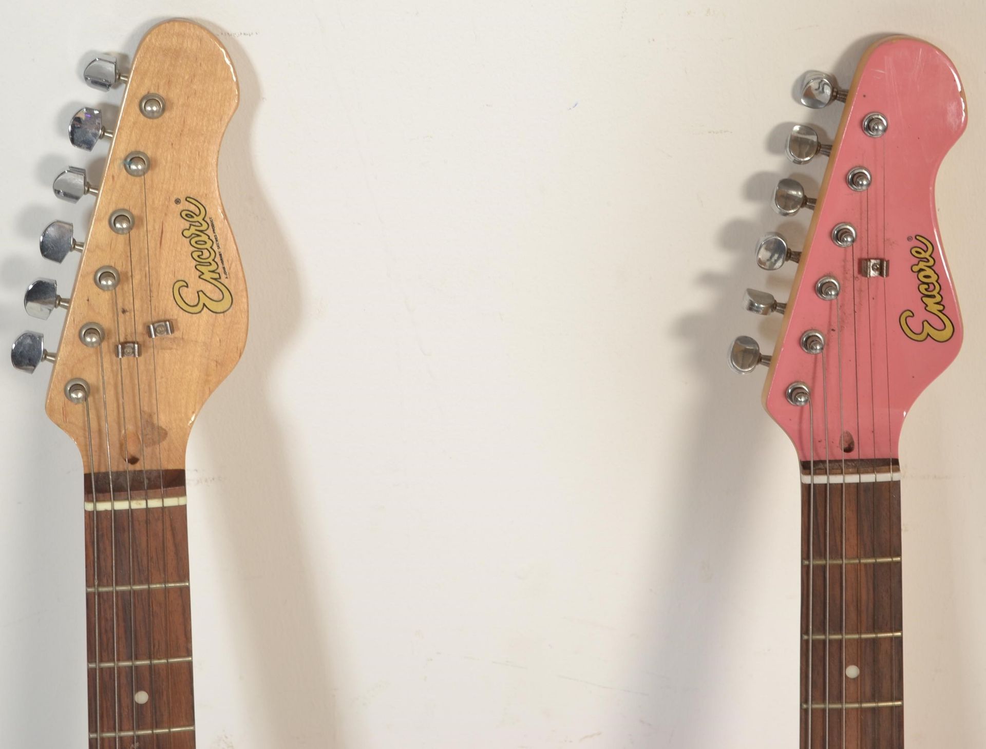 Two 20th Century Stratocaster style six string guitars by Encore, one having a pink body and the - Bild 2 aus 4