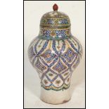 An early 20th Century polychrome Persian bulbous baluster lidded pot / olive jar, raised on