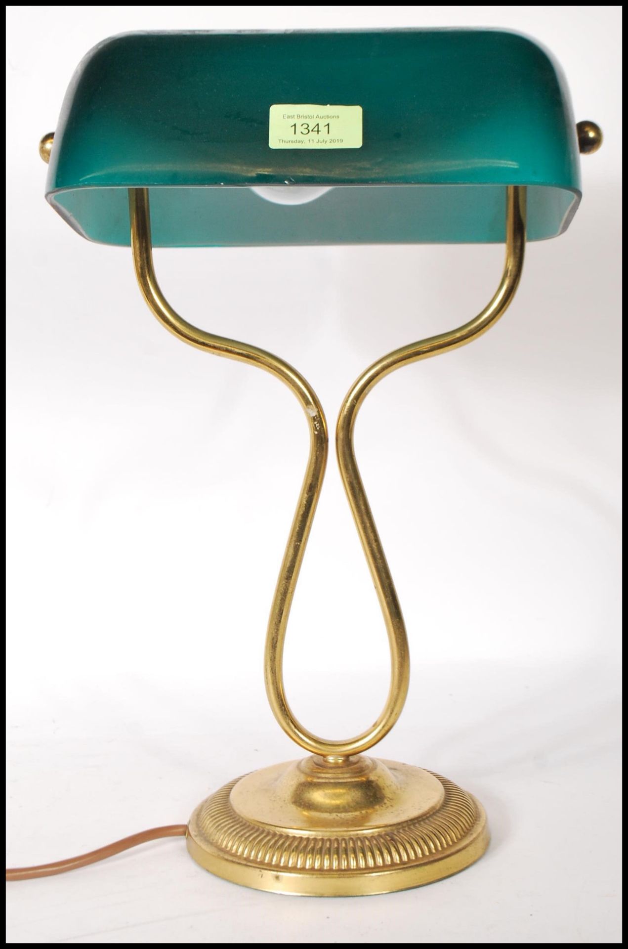 A vintage bankers lamp having a green glass shade raised on a round stepped base with curved brass